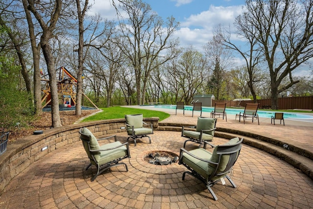 view of patio / terrace featuring a fire pit, fence, a storage unit, an outbuilding, and view of scattered trees