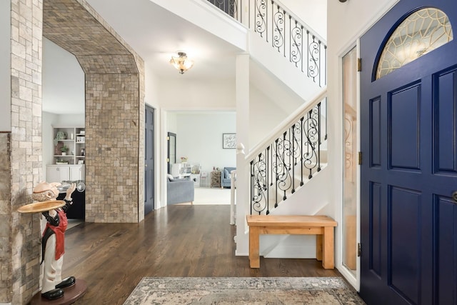 foyer featuring a towering ceiling, wood finished floors, and stairs