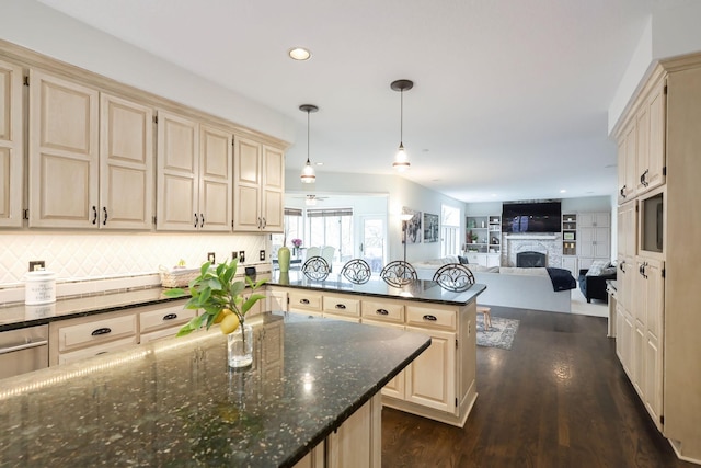 kitchen featuring a peninsula, a fireplace, cream cabinets, backsplash, and dark wood finished floors