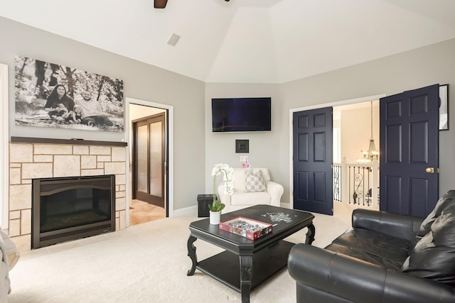living room featuring carpet flooring, lofted ceiling, a stone fireplace, baseboards, and a chandelier