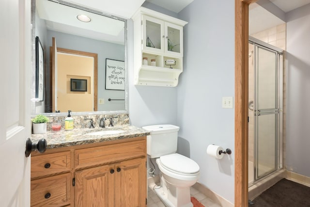 full bathroom with a stall shower, toilet, vanity, baseboards, and tile patterned floors