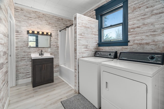 305 Pierson Ave, New Richmond, WI 54017 - washroom featuring washing machine and clothes dryer, a sink, wood walls, healthy amount of natural light, and light wood finished floors