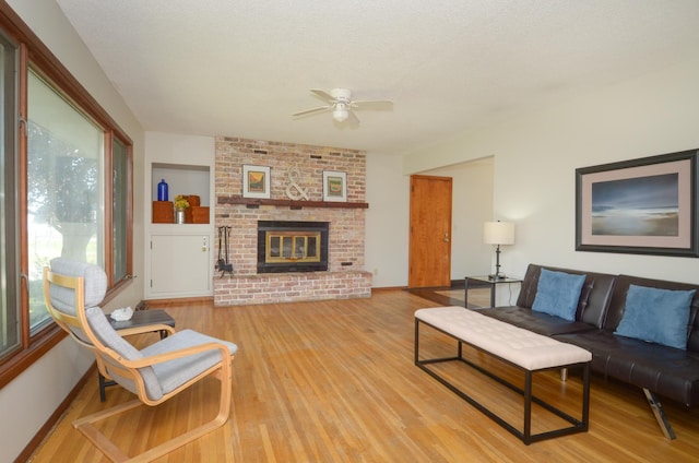 living room with ceiling fan, light wood finished floors, a fireplace, and baseboards
