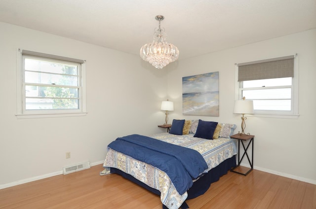 bedroom with wood finished floors, a chandelier, and baseboards