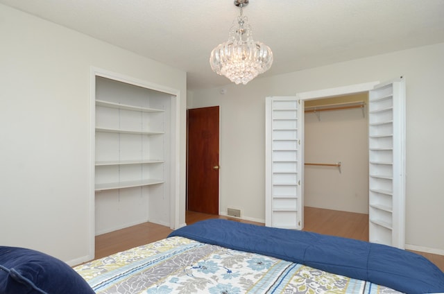 bedroom with wood finished floors and a chandelier