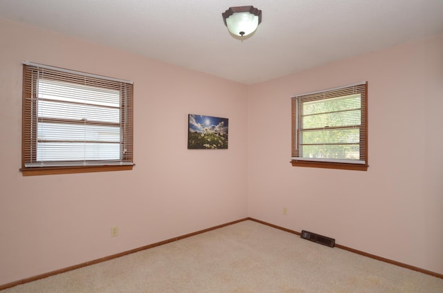 empty room featuring light carpet and baseboards