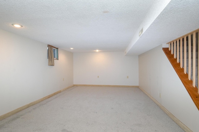 finished below grade area featuring light colored carpet, a textured ceiling, recessed lighting, and baseboards