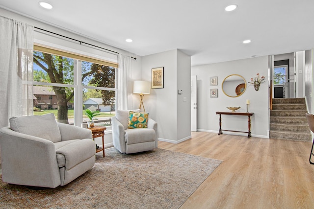 sitting room with plenty of natural light, wood finished floors, recessed lighting, stairs, and baseboards