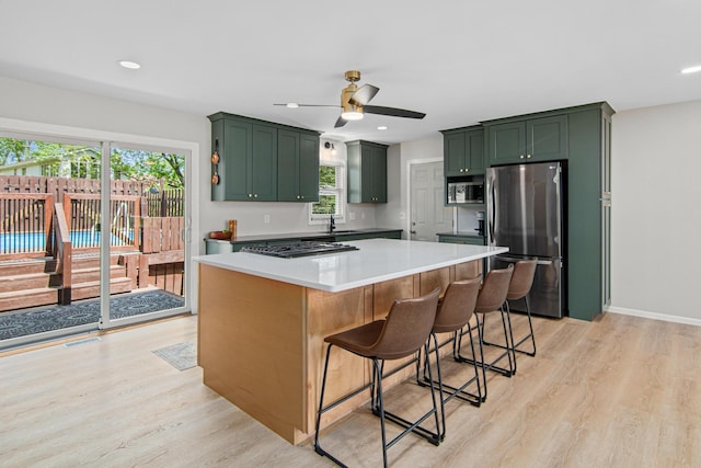 kitchen featuring appliances with stainless steel finishes, green cabinetry, light wood-type flooring, ceiling fan, and recessed lighting