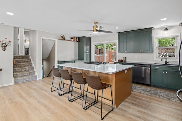 kitchen featuring dishwasher, light wood finished floors, a kitchen island, a kitchen breakfast bar, and recessed lighting