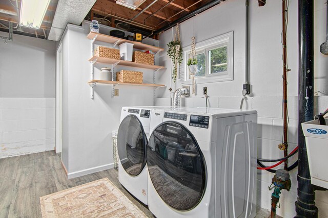 laundry room with washing machine and clothes dryer, wood finished floors, and concrete block wall
