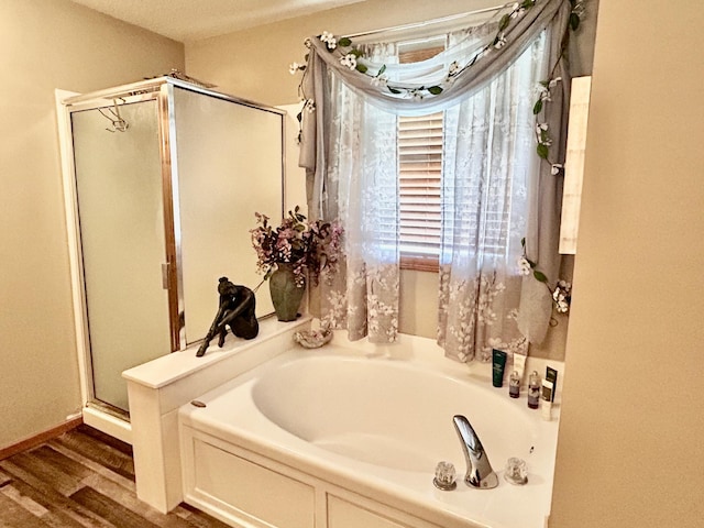 full bath featuring a shower stall, a garden tub, and wood finished floors