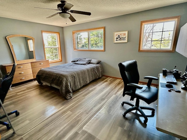 bedroom with a textured ceiling, wood finished floors, baseboards, and ceiling fan