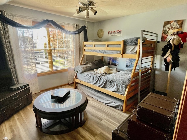 bedroom with wood finished floors, a textured ceiling, and a ceiling fan