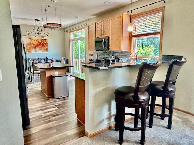 7263 Falmouth Curv, Shakopee, MN 55379 - kitchen with dark countertops, a peninsula, backsplash, baseboards, and hanging light fixtures