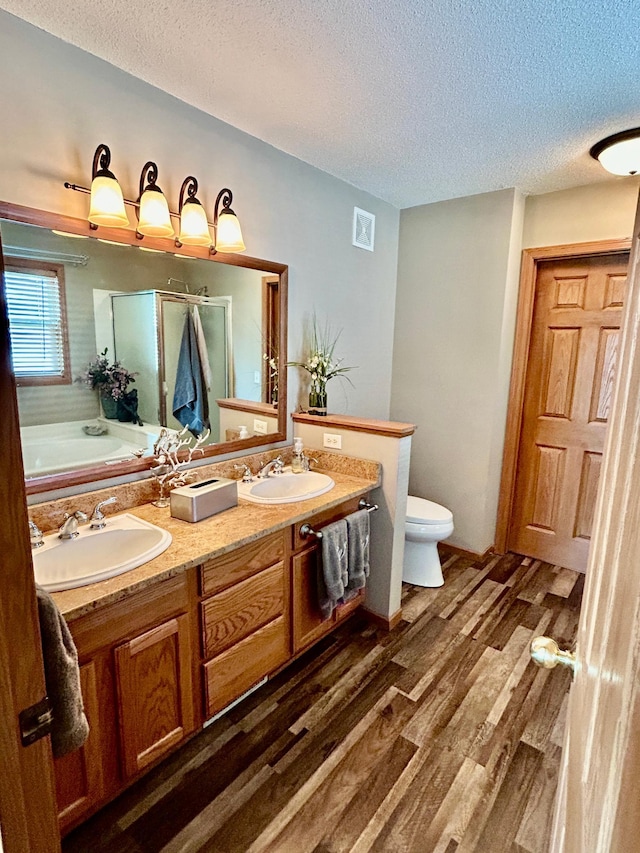 7263 Falmouth Curv, Shakopee, MN 55379 - bathroom with a textured ceiling, wood finished floors, double vanity, toilet, and a stall shower