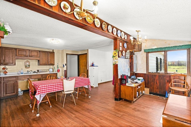 dining space with a textured ceiling, wood finished floors, a chandelier, and lofted ceiling