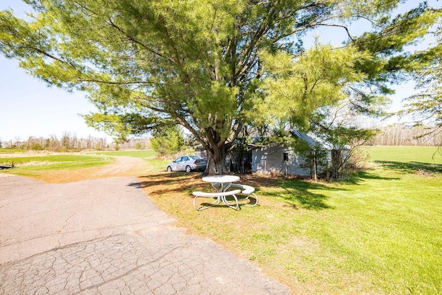 view of property hidden behind natural elements with a front yard and asphalt driveway
