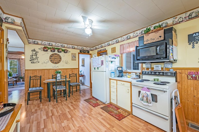 kitchen featuring white appliances, wainscoting, wooden walls, ceiling fan, and light wood-style floors
