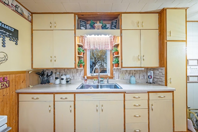 kitchen with a sink, light countertops, a wainscoted wall, and wood walls