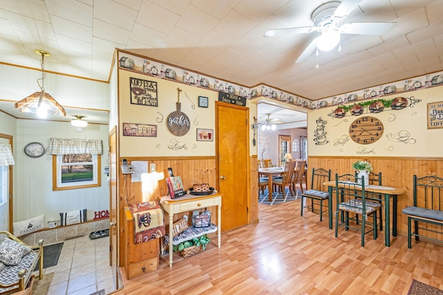 dining space featuring a ceiling fan, wood walls, wainscoting, and wood finished floors