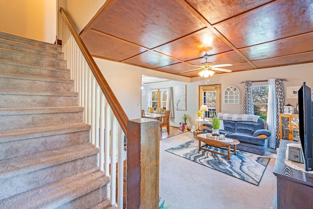 carpeted living area with stairway and ceiling fan