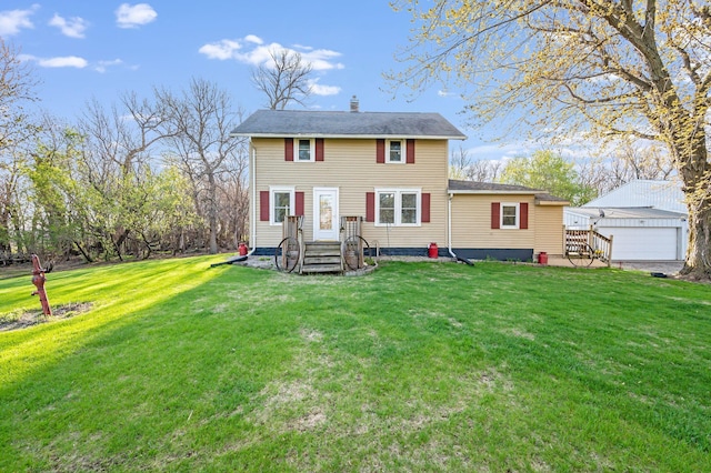 view of front of home with a front lawn, a detached garage, a chimney, and an outbuilding