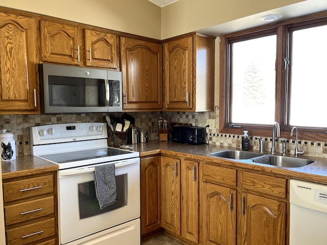 kitchen with brown cabinets, white appliances, decorative backsplash, and a sink