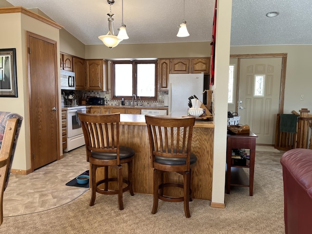 kitchen with decorative light fixtures, a breakfast bar, white appliances, a peninsula, and light carpet