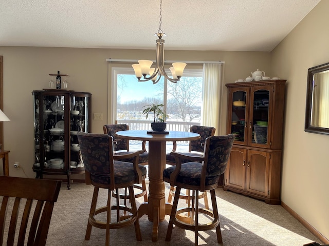 dining area featuring light colored carpet, a textured ceiling, and a notable chandelier