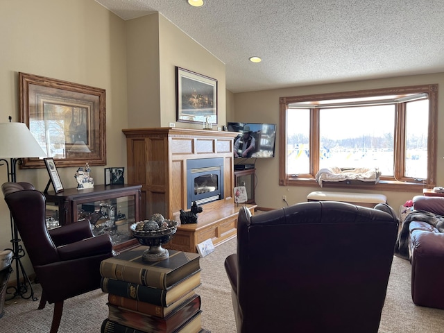 carpeted living room with a glass covered fireplace and a textured ceiling