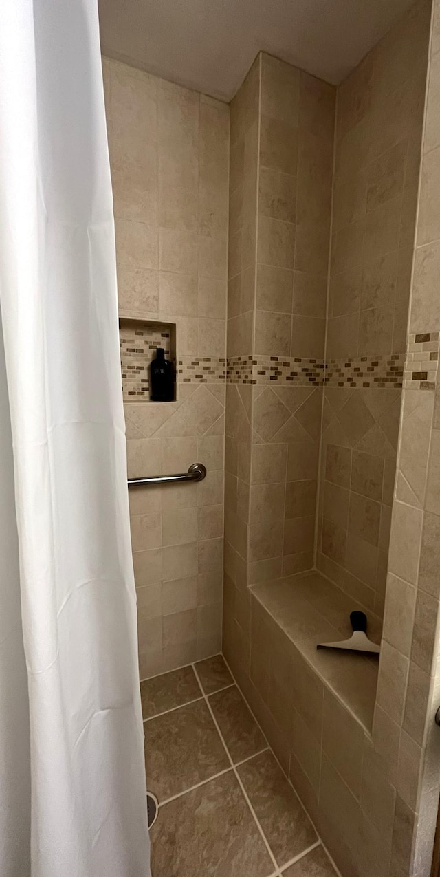 full bath with tiled shower and tile patterned flooring