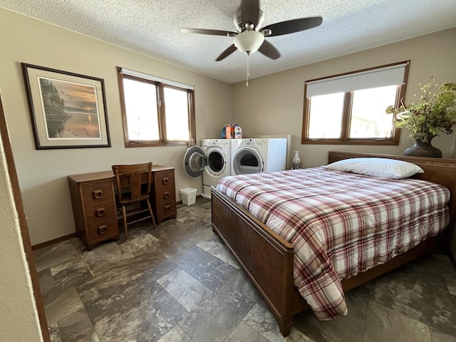 bedroom featuring multiple windows, washer and clothes dryer, stone finish flooring, and a textured ceiling