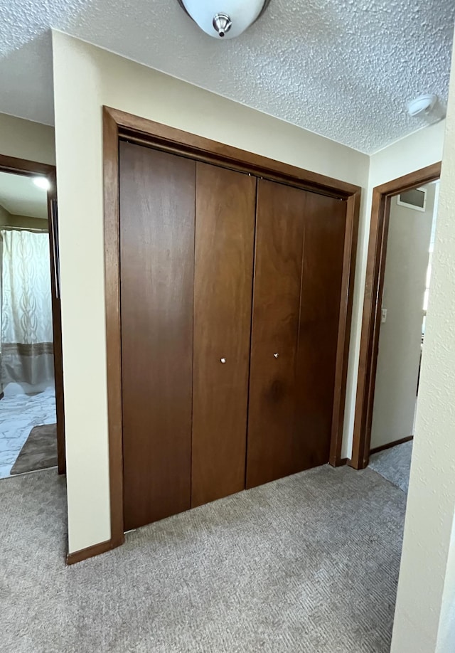 unfurnished bedroom with light colored carpet, a closet, a textured ceiling, and baseboards