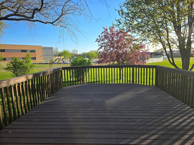 wooden deck featuring a playground and a lawn