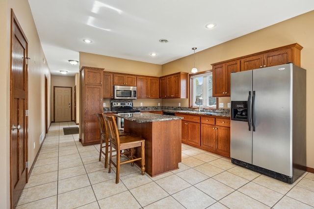 173 Cardinal Ln, Clearwater, MN 55320 - kitchen featuring appliances with stainless steel finishes, brown cabinetry, light tile patterned flooring, a kitchen island, and a kitchen breakfast bar