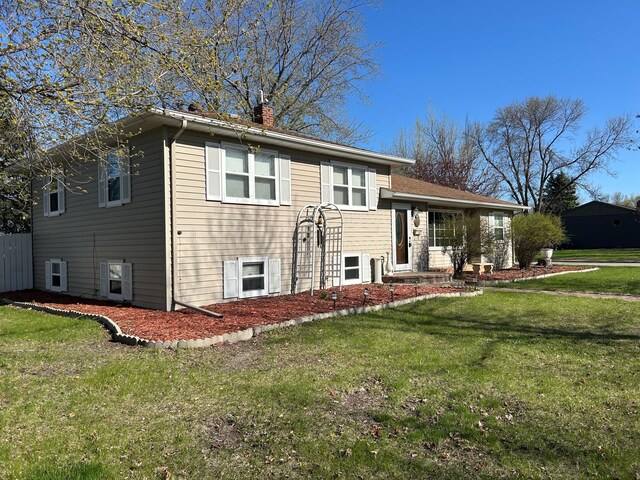 tri-level home featuring a chimney and a front yard