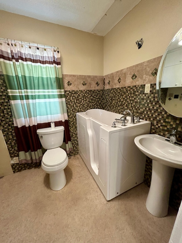 324 Maple Ave S, Thief River Falls, MN 56701 - bathroom featuring a bath, tile walls, toilet, a wainscoted wall, and a textured ceiling