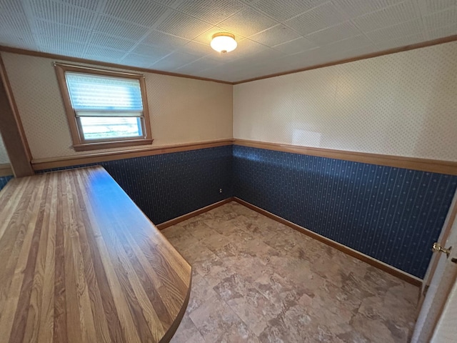 324 Maple Ave S, Thief River Falls, MN 56701 - empty room featuring a wainscoted wall, ornamental molding, baseboards, and wallpapered walls