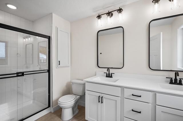 2140 Arkwright St, Maplewood, MN 55117 - bathroom with toilet, double vanity, a shower stall, and baseboards