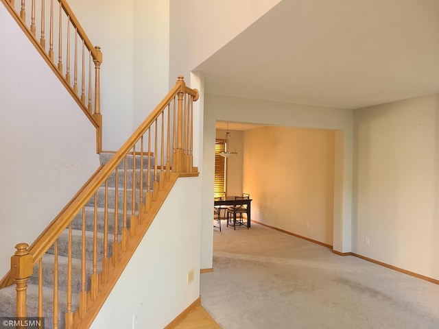 stairs featuring carpet floors, baseboards, and a towering ceiling