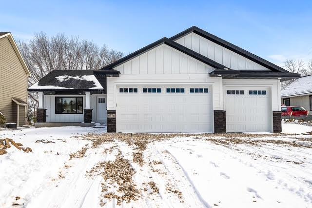 view of front of house with board and batten siding, a garage, and stone siding