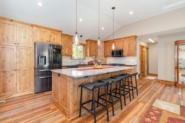 27667 Bay Shore Dr NW, Isanti, MN 55040 - kitchen featuring stainless steel appliances, a sink, light wood finished floors, a kitchen island, and backsplash