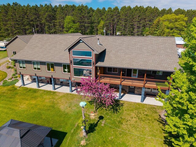 27667 Bay Shore Dr NW, Isanti, MN 55040 - rear view of property featuring a patio, a yard, a shingled roof, and a view of trees
