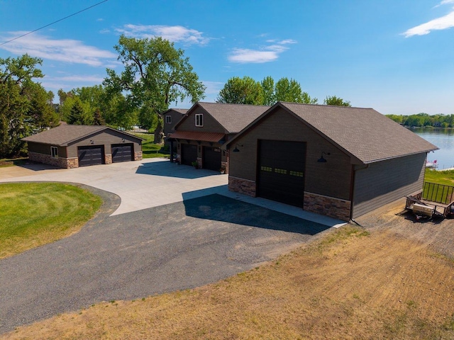 27667 Bay Shore Dr NW, Isanti, MN 55040 - view of front of house featuring stone siding, an outdoor structure, a water view, driveway, and roof with shingles