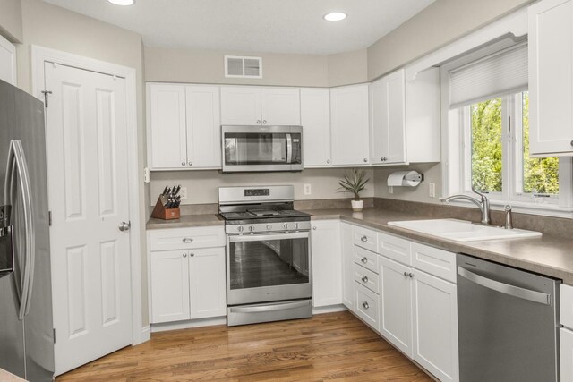 5057 Linden Trl N, Lake Elmo, MN 55042 - kitchen featuring appliances with stainless steel finishes, a sink, white cabinets, recessed lighting, and light wood-style flooring