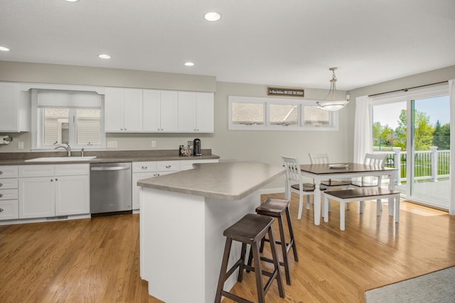 5057 Linden Trl N, Lake Elmo, MN 55042 - kitchen featuring stainless steel dishwasher, a sink, light wood-style flooring, a kitchen breakfast bar, and white cabinets
