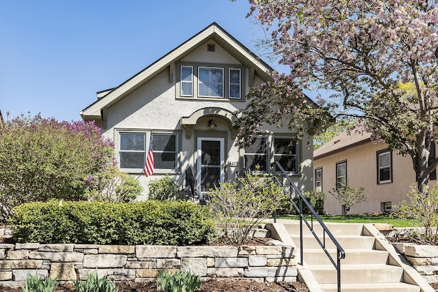 bungalow-style house featuring stucco siding and stairs
