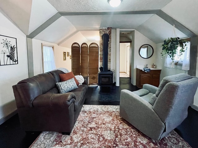 506 2nd St S, Tower, MN 55790 - living room with vaulted ceiling, a wood stove, dark wood-style floors, a textured ceiling, and baseboards