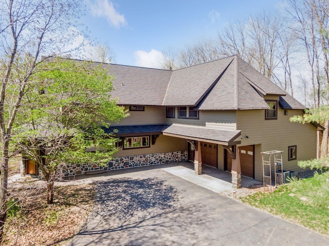 view of front of property with driveway, roof with shingles, and a garage